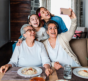 Foto de dos abuelas tomándose una selfie con las nietas durante la comida